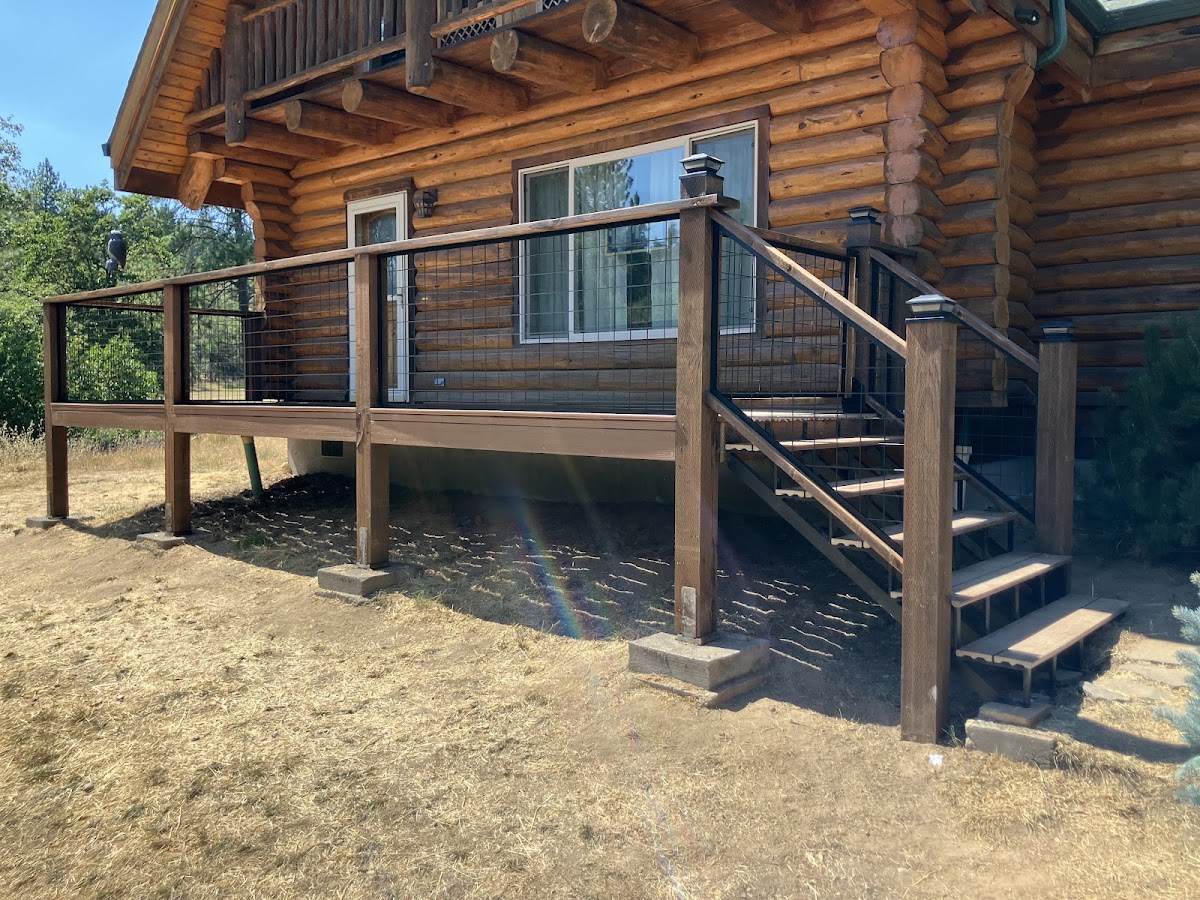 New deck and railing built onto a log cabin by Gibbons Construction